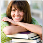 Smiling student resting on books.