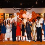 A group of people standing on stage in front of balloons.