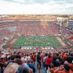A crowd of people watching an orange and white football game.