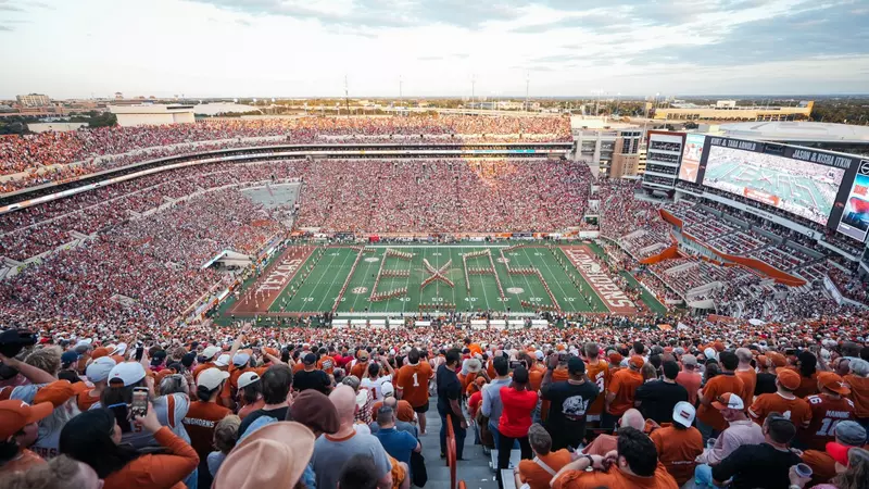 A crowd of people watching an orange and white football game.