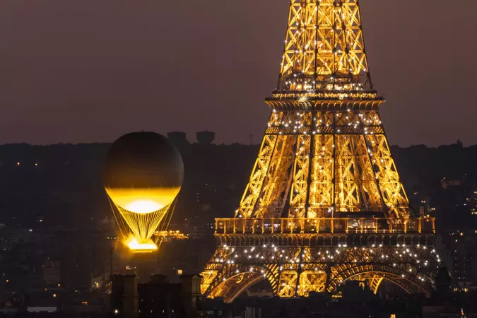 A hot air balloon flying in front of the eiffel tower.
