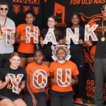 A group of people holding up letters that spell out " thank you ".